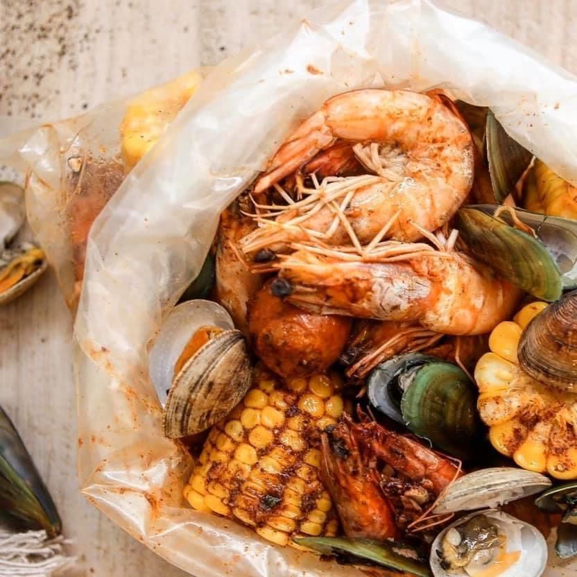An opened bag of head-on shrimp, green mussels, clams and corn