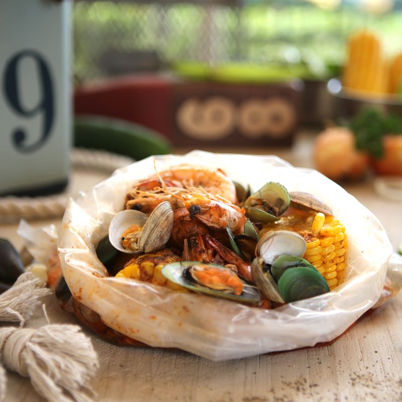 A seafood boil of shrimp, clams, mussels and corn poured on a table beside rope and lime
