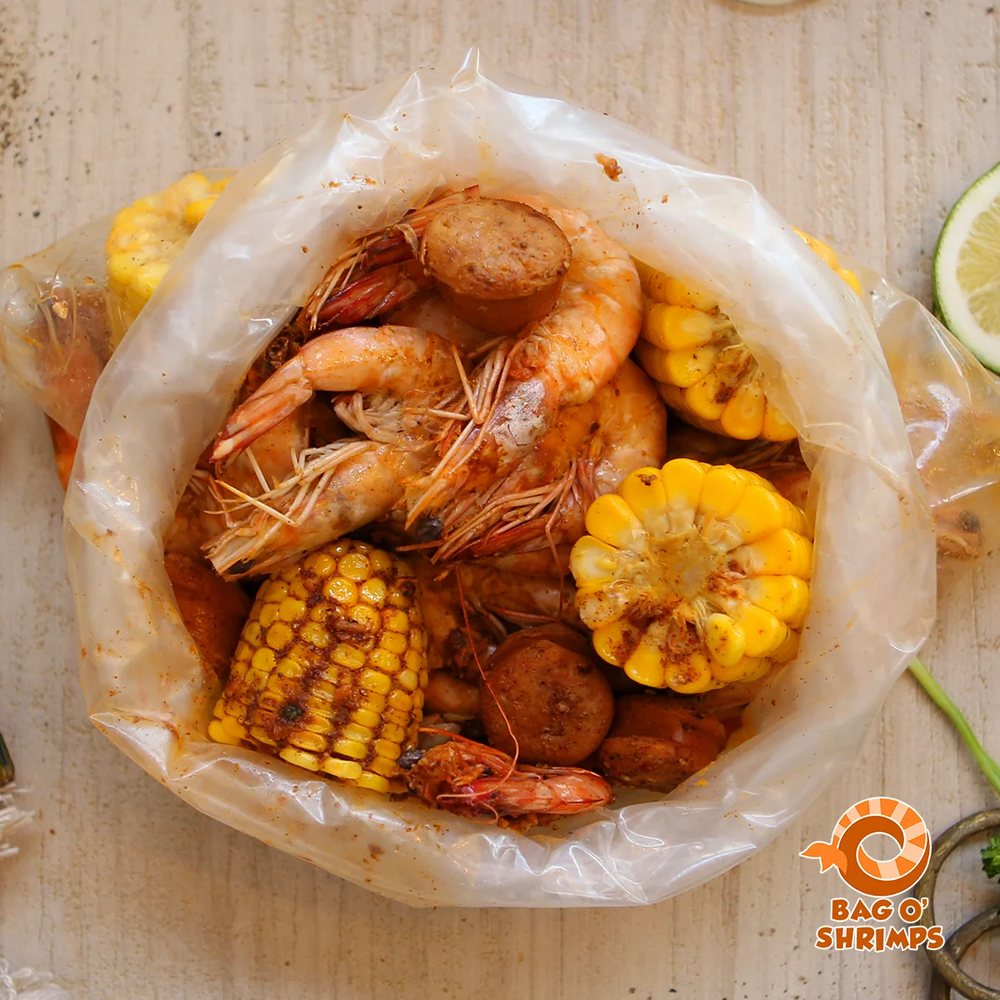 Overhead view of an open bag of head-on shrimp, sausage and spiced corn